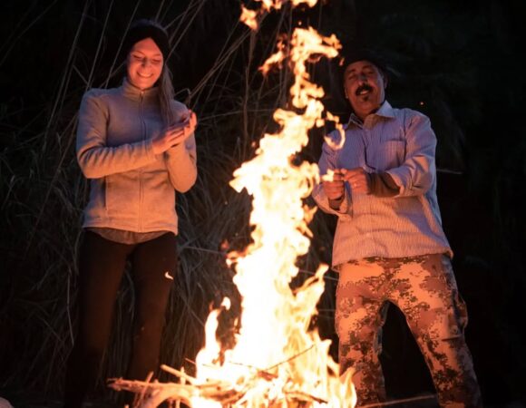 Guide and hiking guest singing at fire during hiking adventure