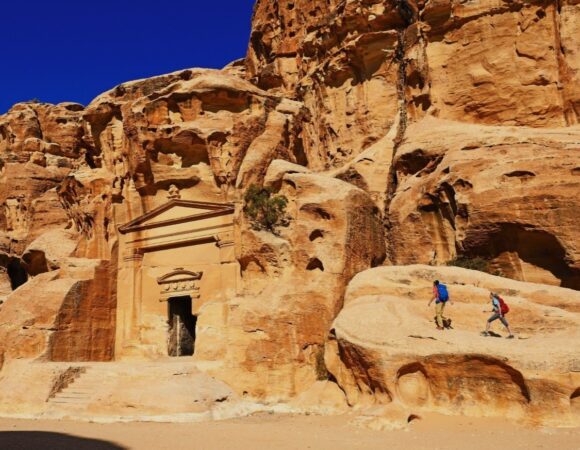 Two hikers and a facade in Little Petra Jordan