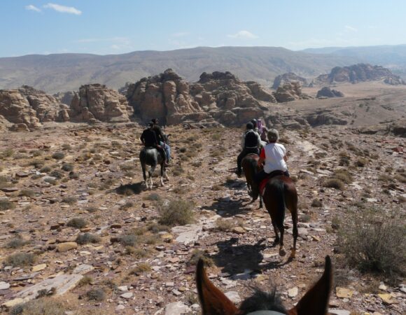 Group of horse riders in Little Petra with mountains in the distance