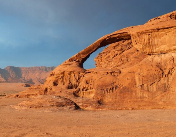 Rock bridge in Wadi Rum desert with mountains in the back